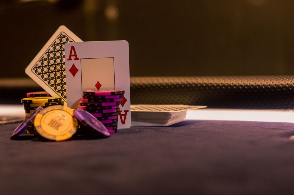 Ace of diamonds and poker chips on a dark casino table